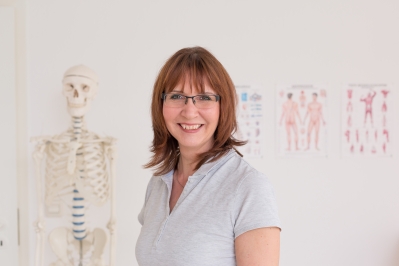 Portrait von Annett Hannemann im Praxisraum, im Hintergrund leicht verschwommen ein Skelett